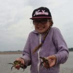 a young girl holding two crabs in her hands