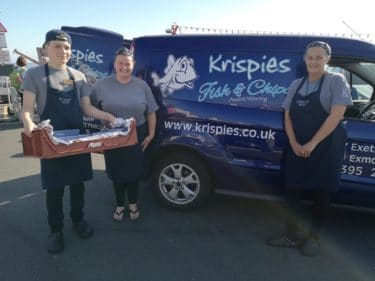 people standing next to a fish and chip van