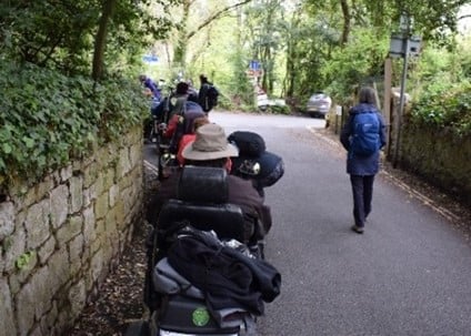 People using disability scooters on a road.