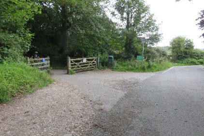 A road with a lay-by area and a path leading into a wood.