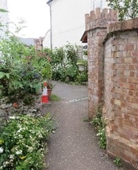 A path between a brick wall and a hedge.