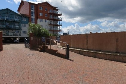 A blue, white and brown building near an open paved area.