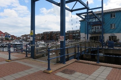 A foot bridge to a blue building.