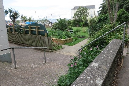 Some steps with a hand rail and a garden at the bottom.