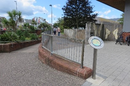 A pavement with a metal fence and a building on the right.