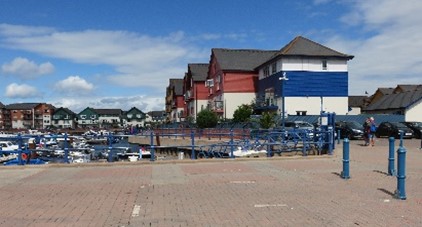 A marina with a large building on the right and blue railings in the foreground.