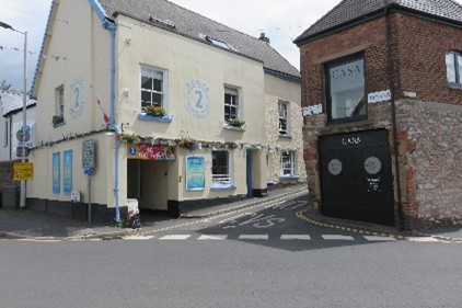 A road junction by a pale yellow building and a brick building.