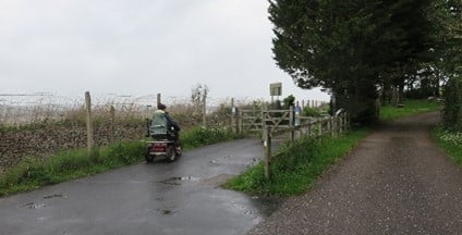 Two paths separated by a wooden fence with trees in the background.