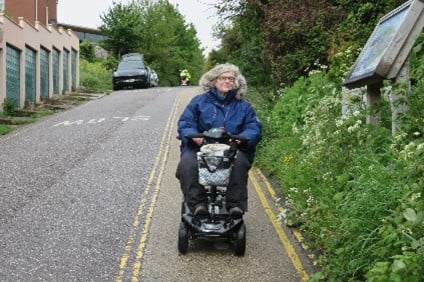 A person on a mobility scooter on a road.